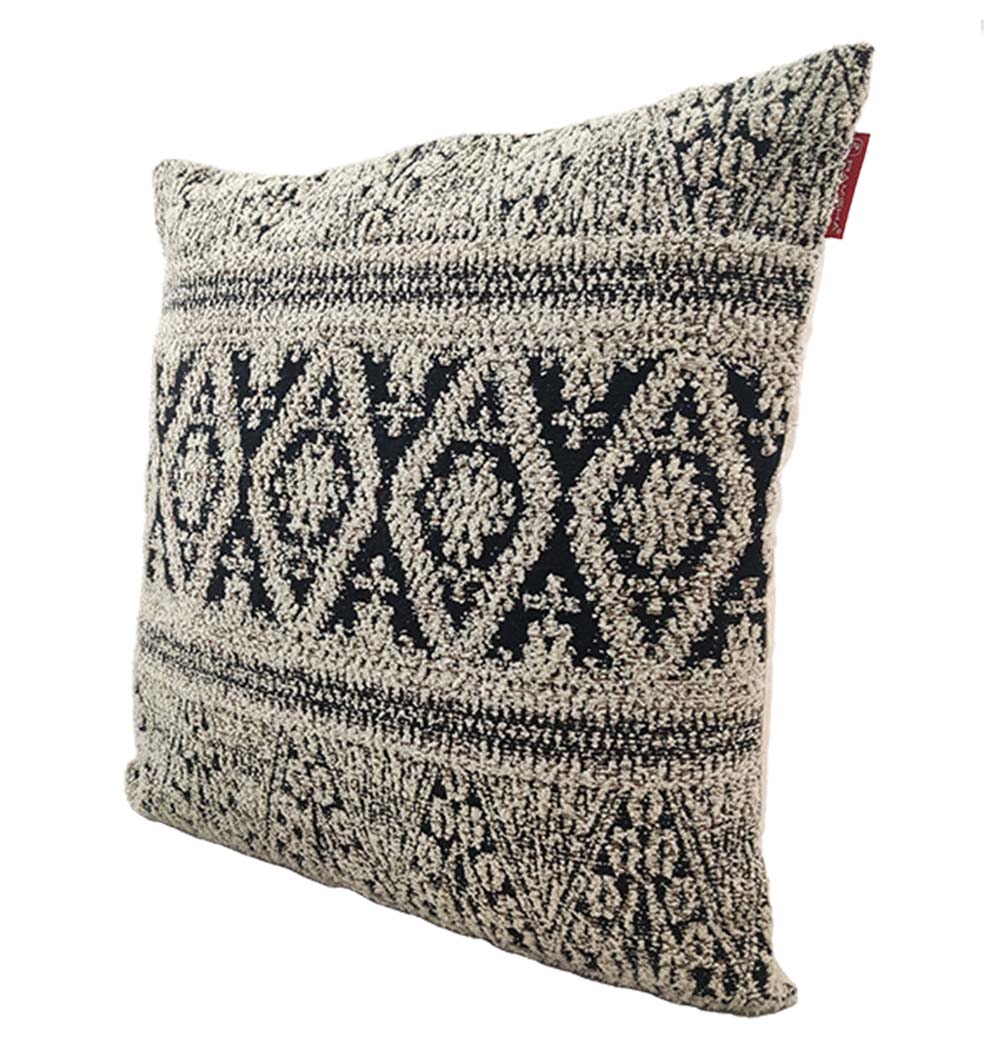 The RAMSHA HOME Boho Cushion With Small Tassels CS-204 is a square decorative pillow with a textured black and white geometric pattern, featuring diamond and triangular designs plus a soft woven finish and small red tag on the edge.