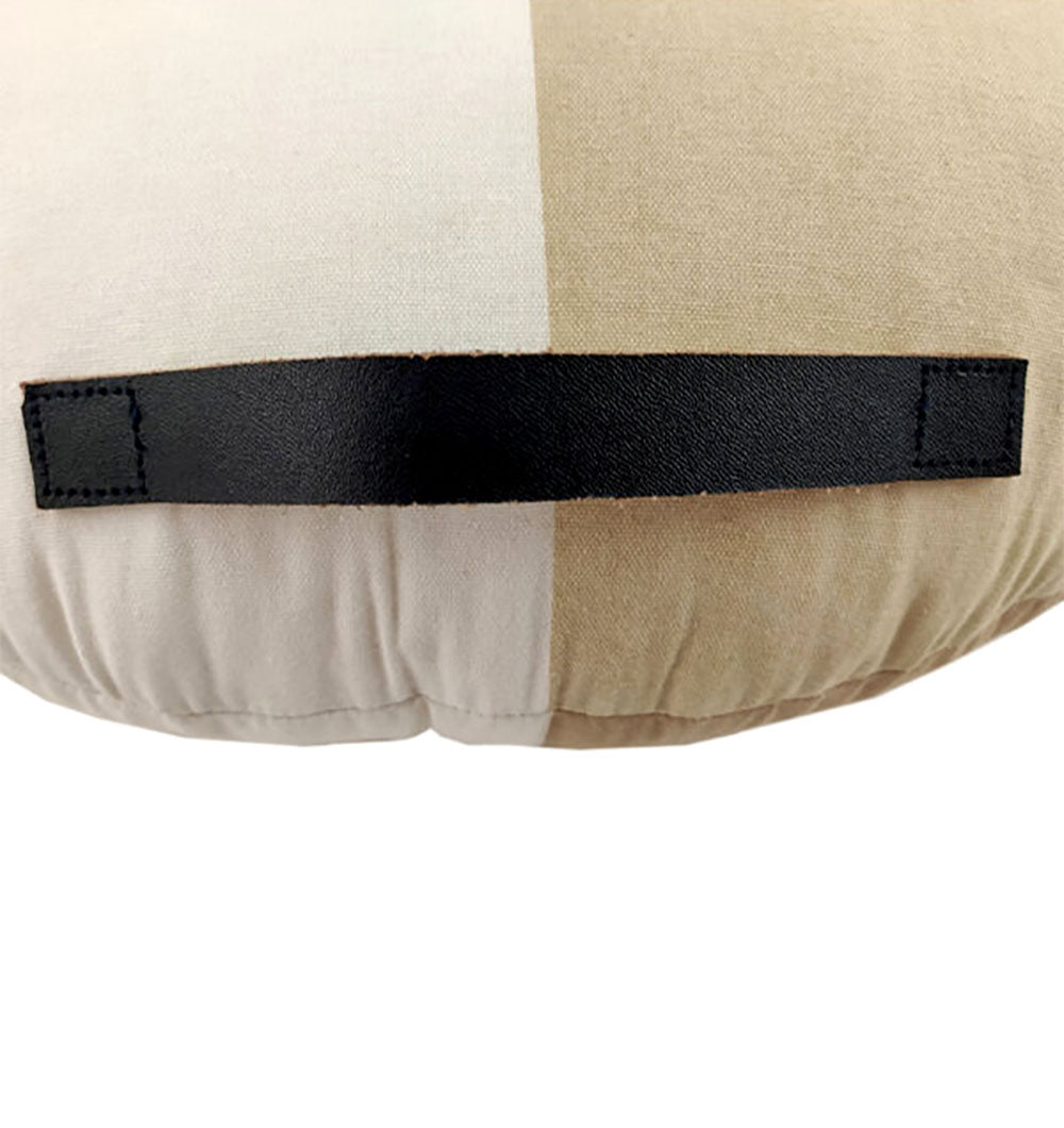 A close-up of the RAMSHA HOME Round Cotton Cushion CS-225 in beige and off-white, featuring a black rectangular fabric handle stitched horizontally at the center.