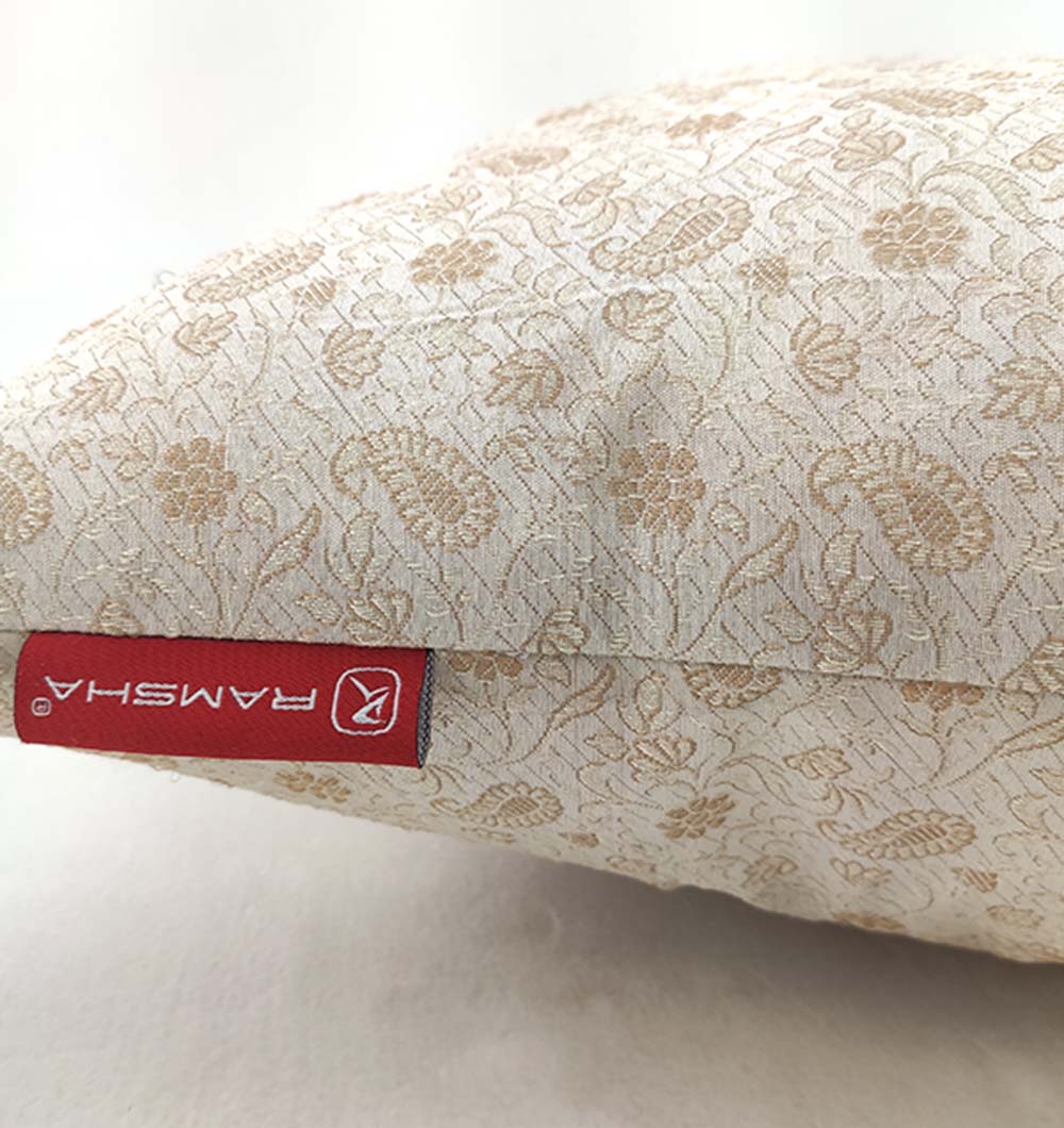 A close-up of a black and gold polyester cushion with tassels by RAMSHA HOME, featuring a plush texture and a branded tag on the edge. The background is a plain, light-colored surface.