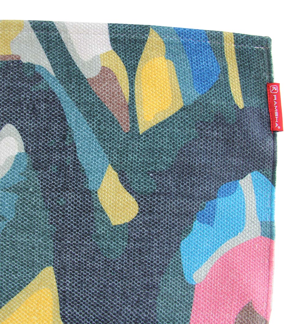 A close-up of the RAMSHA HOME Multi Color Floor Rug DD-035 shows textured fabric with green, yellow, blue, pink, and white abstract shapes and a small red tag sewn into the edge.