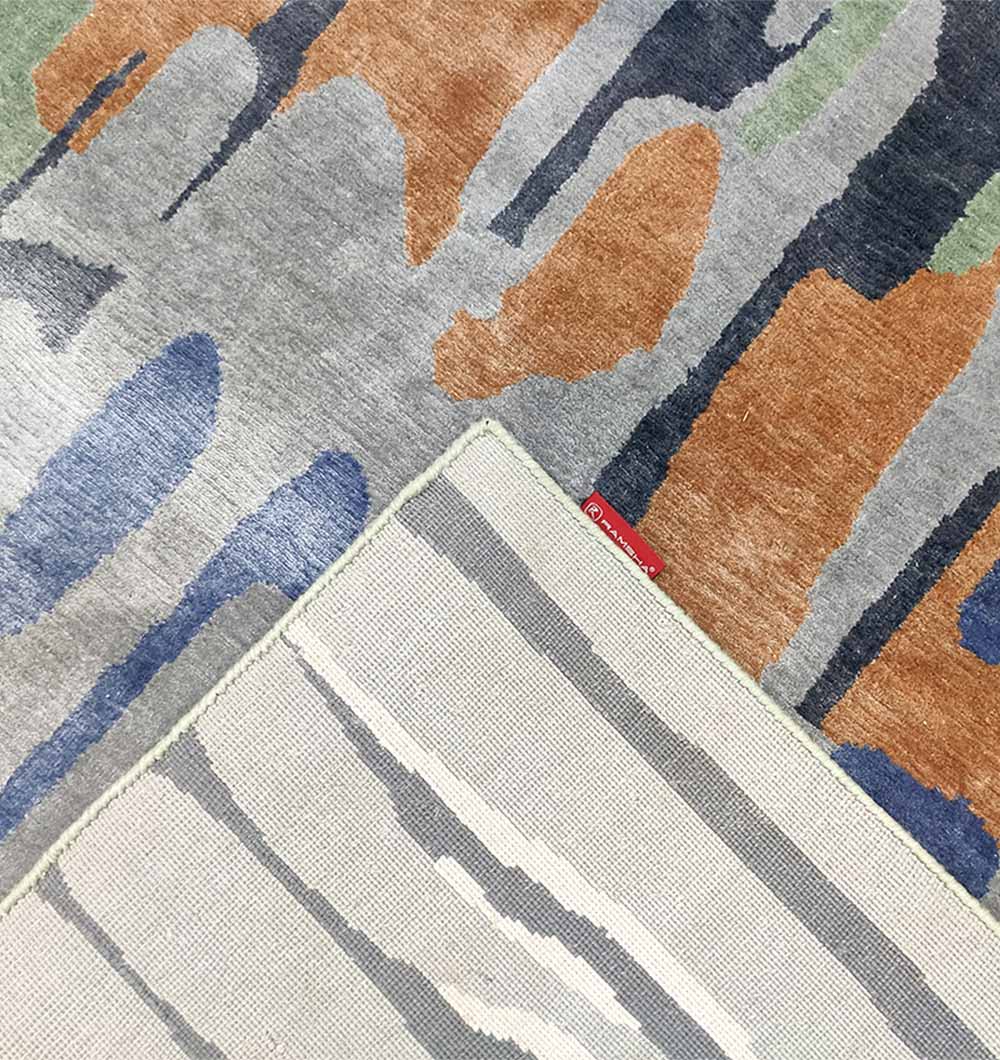 A close-up shows the RAMSHA HOME Decorative Area Carpet Tencil & Cotton Multi Color HKV-09 with orange, blue, gray, and green shapes; a corner is flipped to reveal its beige-gray underside with a red tag. This rug adds modern style to any space.