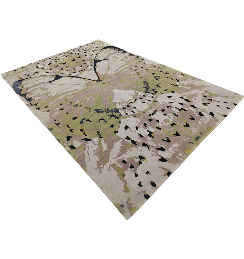 The RAMSHA HOME Butterfly Design Carpet For Every Room HKWV-010 is a hand-knotted area rug with an abstract butterfly pattern in green, beige, black, and subtle pink tones, shown from a low angle.