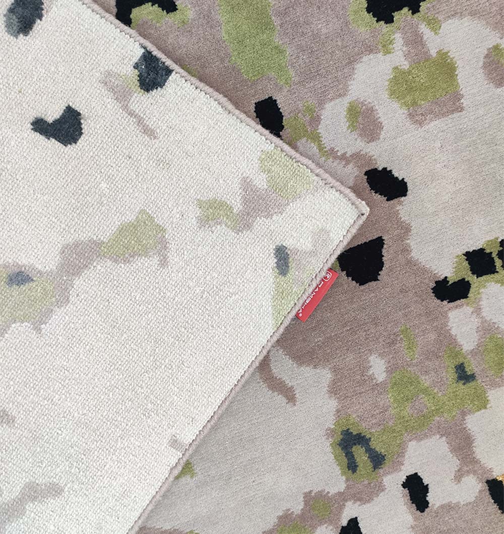 A close-up of the RAMSHA HOME Butterfly Design Carpet HKWV-010 showcases beige, green, black, and white tones. One corner is flipped, revealing the reverse side and a small red fabric tag on the edge.