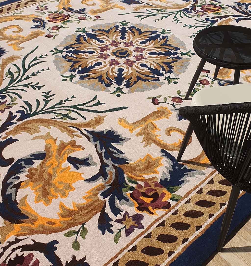 A detailed view of the RAMSHA HOME Polyester & Cotton Hall Decor Rug - HTP 02 (300x400cm) with ornate multicolored patterns, displayed next to a sleek black chair and a round black side table.