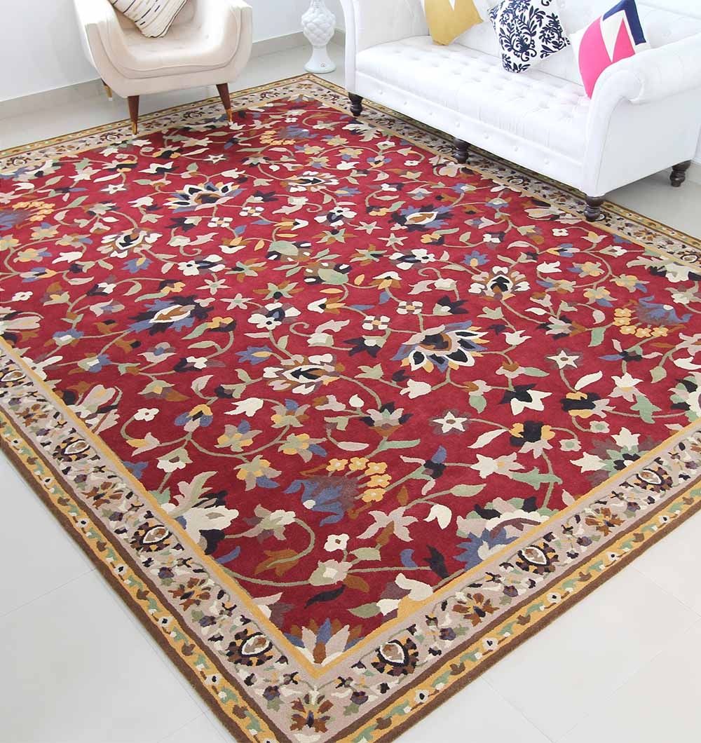 The RAMSHA HOME Wool & Cotton Handmade Area Rug HTW-08, featuring traditional floral patterns in yellow, cream, blue, and green with a decorative border, is displayed on a white floor near a white sofa and cream armchair.