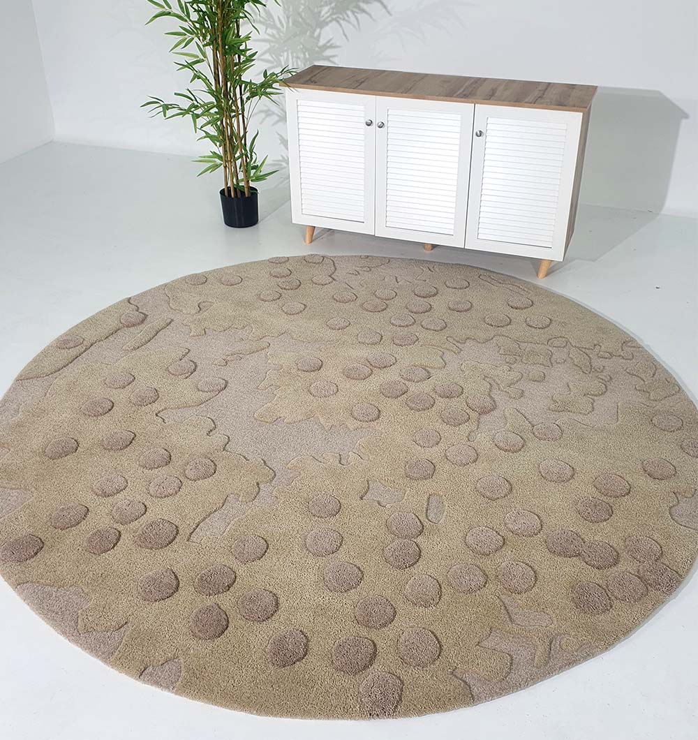 The RAMSHA HOME Round Home Decor Handmade Carpet – HTW-56 with raised circular patterns decorates the floor in front of a white cabinet with wooden top and legs, accented by a potted plant for a minimalist touch.