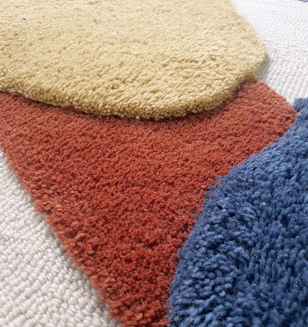 Close-up of the RAMSHA HOME Multicolor Handmade Round Rug HTW 59 (200cm), showcasing textured abstract shapes in beige, rust orange, mustard yellow, and deep blue on a light woven background.