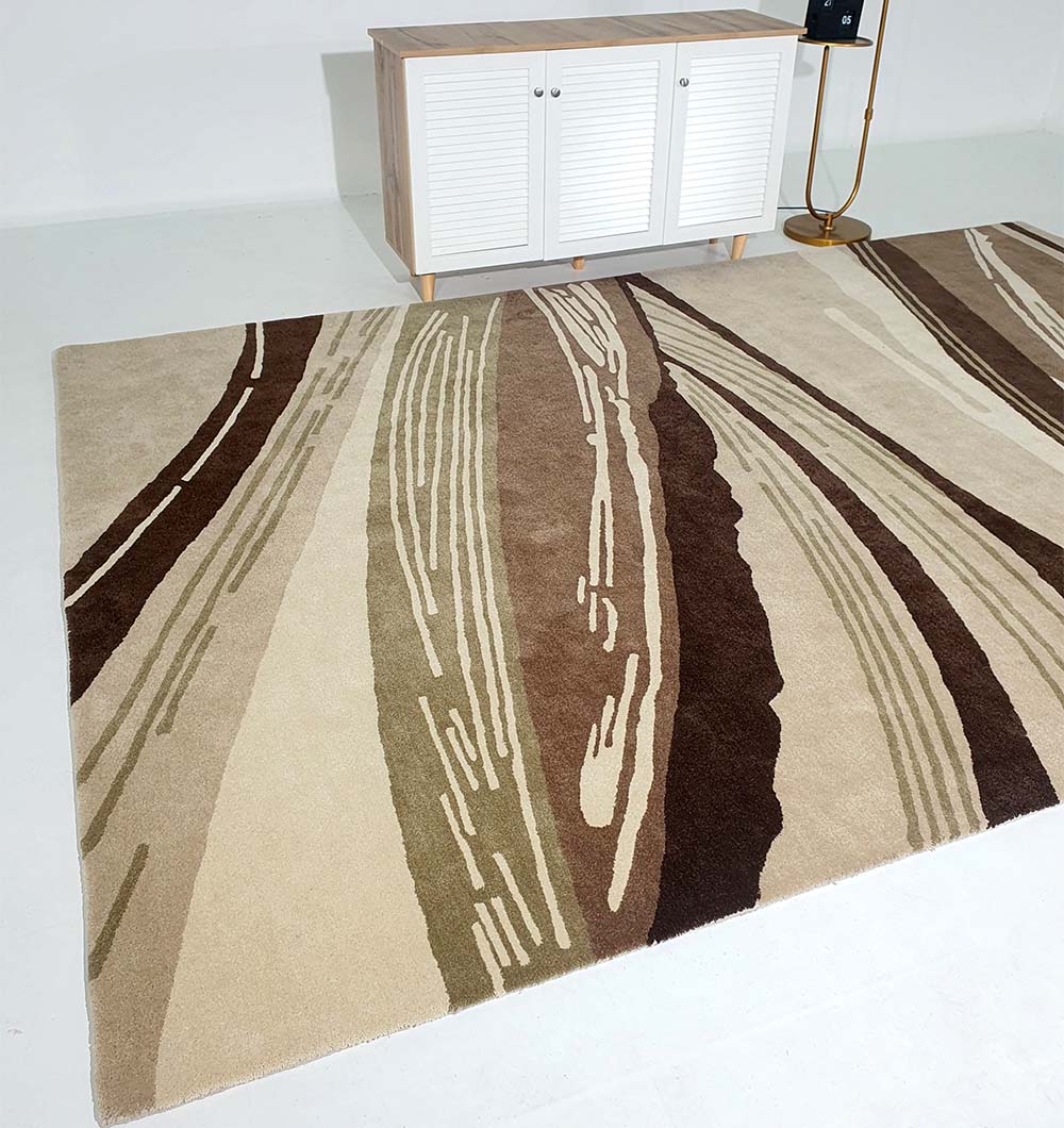 The Striking Pattern Home Decor Handmade Carpet – HTW-61 by RAMSHA HOME, featuring modern wavy patterns in beige, brown, and tan shades, is displayed on a white floor with a light wood cabinet and gold floor lamp nearby.