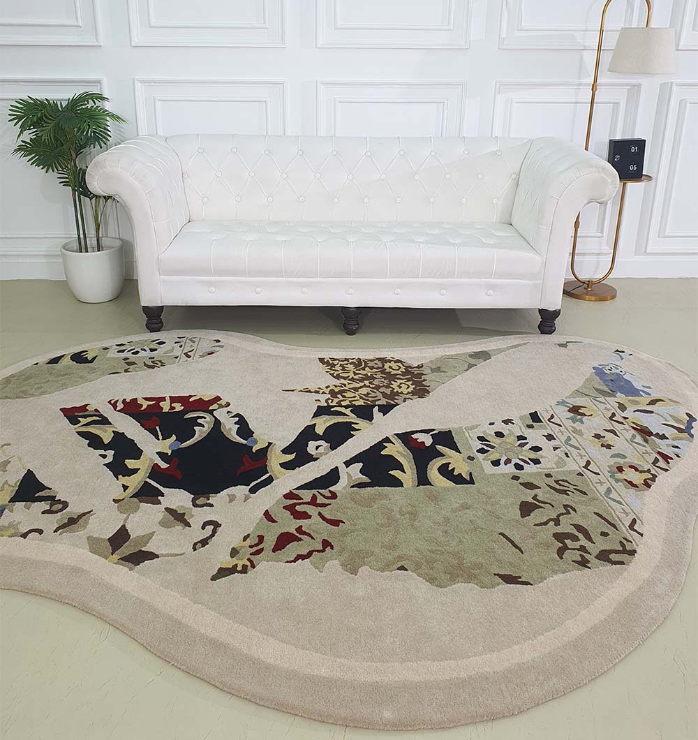 A cream-colored tufted sofa stands against a white paneled wall, with the RAMSHA HOME Unique Unshaped Handmade Carpet For Home Decor HTW-70 in earth tones and muted reds on the floor. A potted plant and floor lamp are nearby.