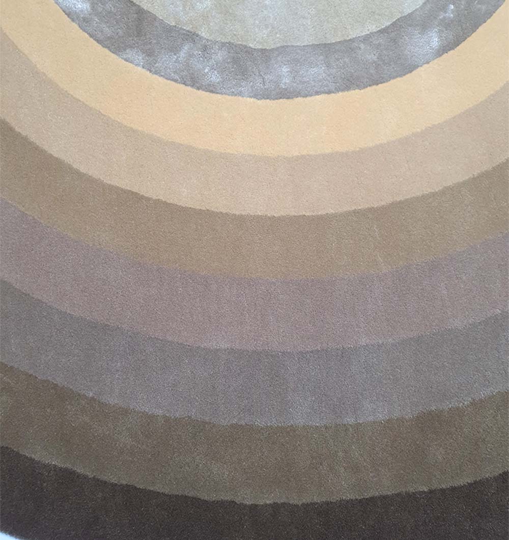 The RAMSHA HOME Multi Color Handmade Hand Tufted Carpet HTWV-49 showcases concentric semi-circles in earthy browns, tans, and grays, forming a striking gradient from light at the top to dark at the bottom.