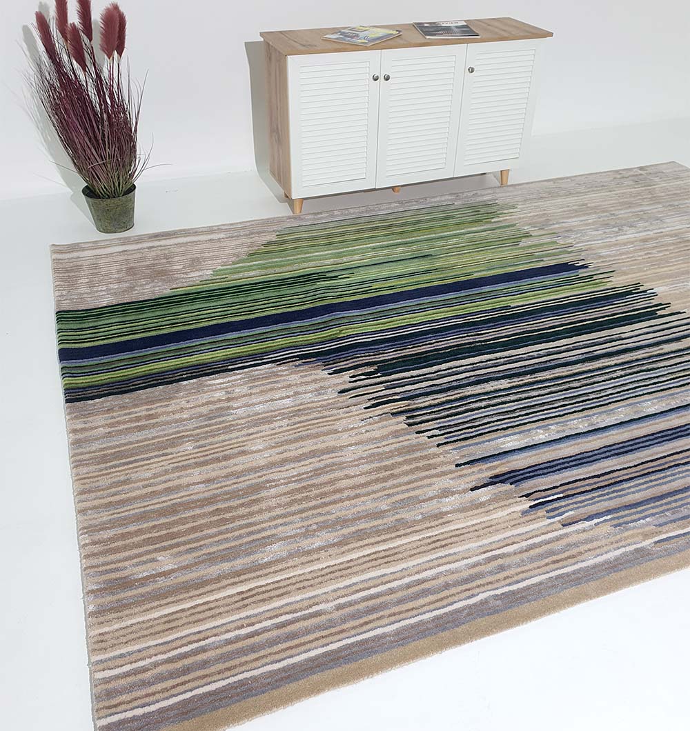 A modern room with the RAMSHA HOME Striped, Beige & Grey Rug (HTWV-52) featuring navy and green accent bands, a wooden cabinet with white doors, and tall burgundy pampas grass in a vase on a white floor.