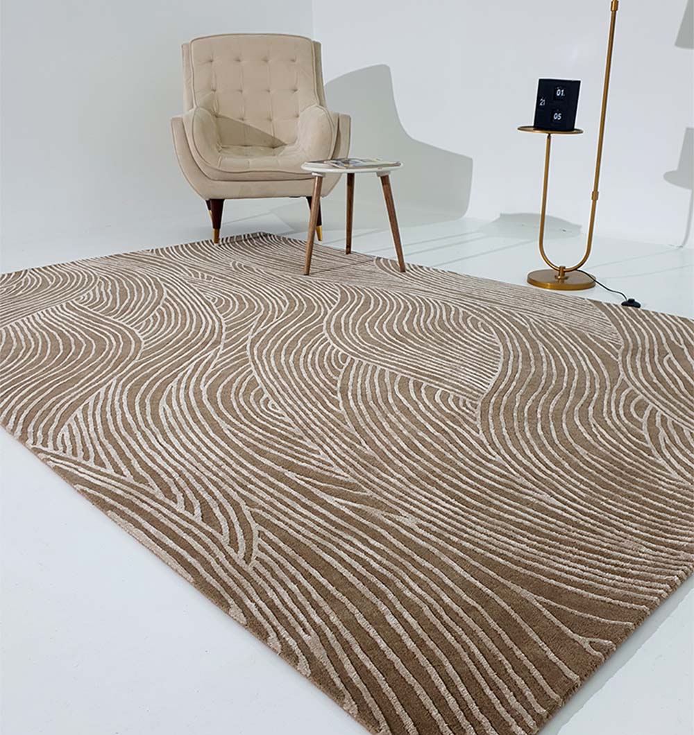 A modern room with a beige armchair, round side table, gold floor lamp, and the RAMSHA HOME Handmade Beige Handtufted Area Rug HTWV-53 featuring wavy white lines on a white floor and background.