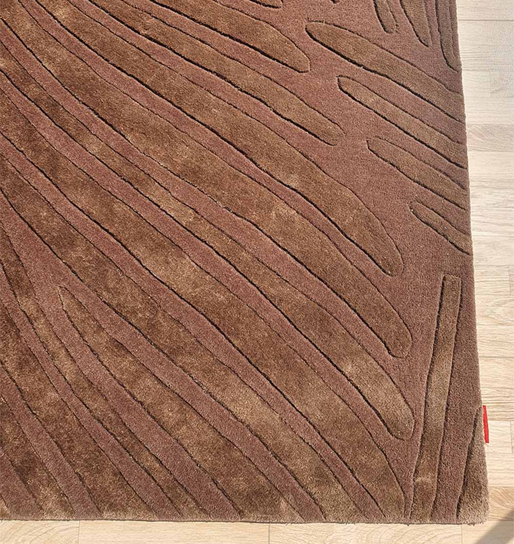 A close-up of the RAMSHA HOME Premium Quality Handmade Carpet HTWV-79, a chocolate brown hand-tufted wool rug with raised wavy lines, shown on a light wooden floor.