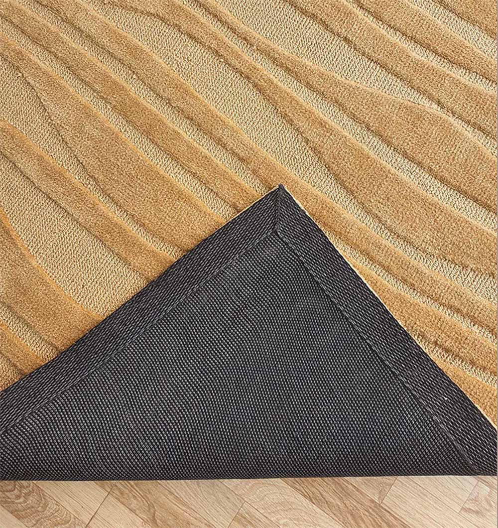 A close-up of the RAMSHA HOME Rectangle Beige Color Carpet MNR-03 shows its light brown abstract texture and a corner flipped to reveal black non-slip backing, placed on a light wooden floor for a modern neutral look.