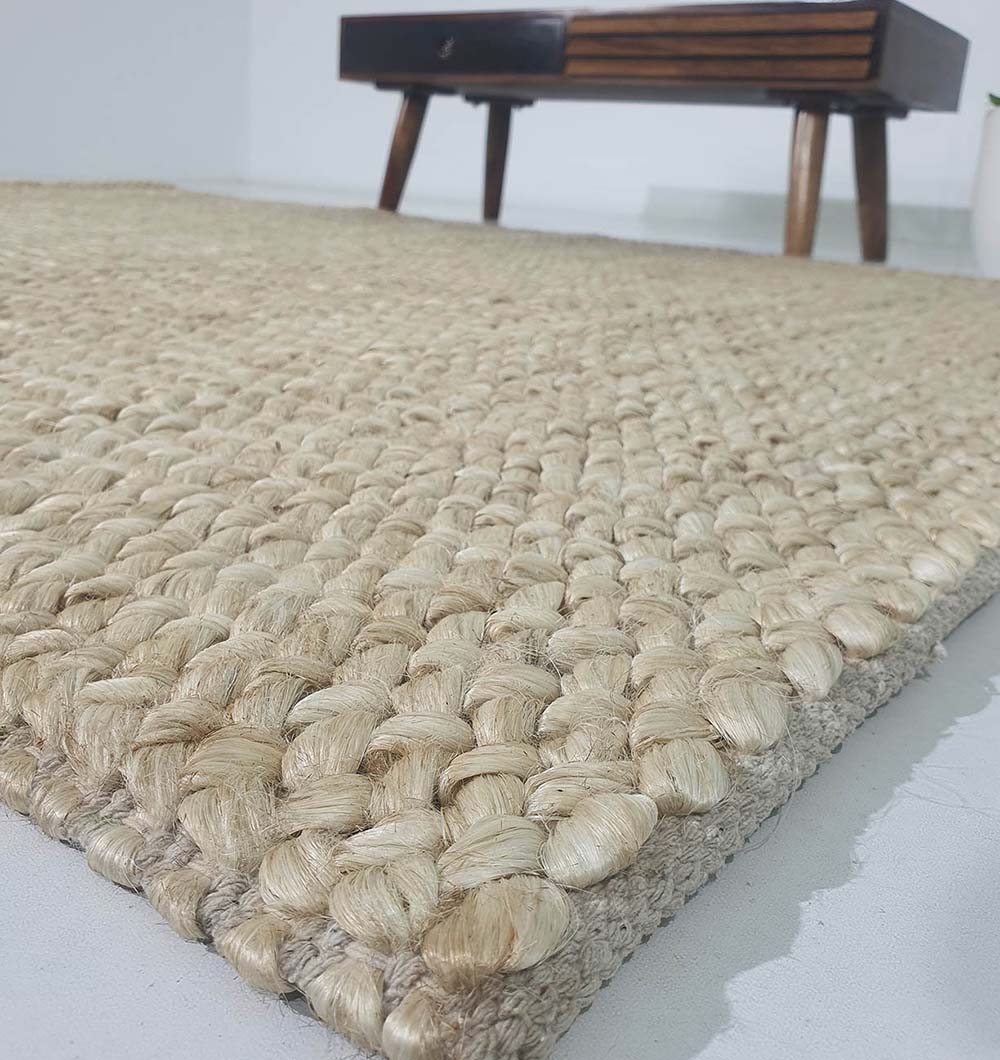 Close-up of the RAMSHA HOME Bleach Color Woven Floor Rug For Home Decor SR-037 on a light floor, with a wooden table in the background. The handmade rug’s chunky, detailed texture enhances your space.