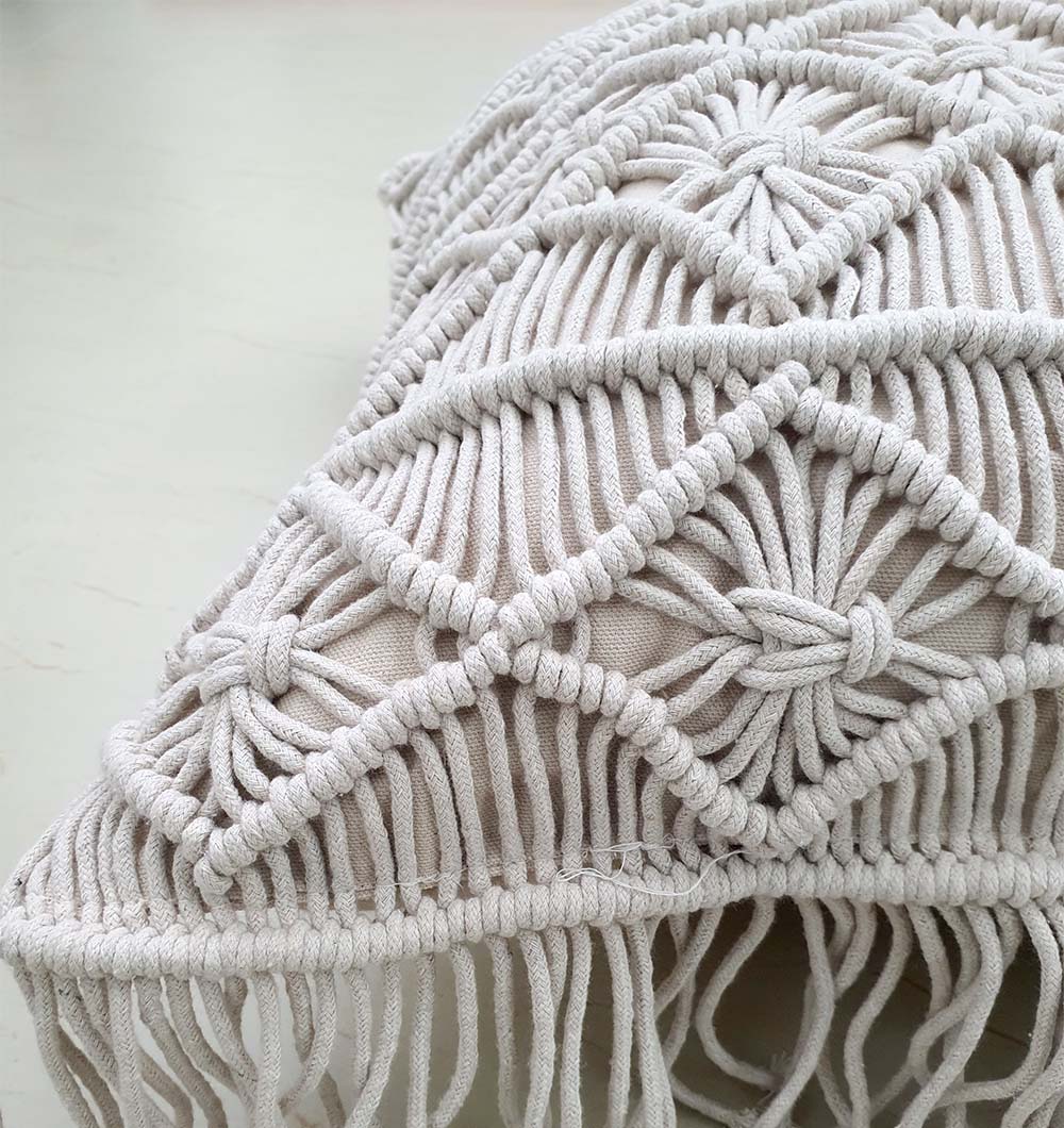 Close-up of the RAMSHA HOME Cotton Cushion CS-276, featuring an intricate macramé cover with geometric patterns and tasseled fringes—a stylish handmade decor accent for your home.