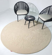 A modern minimalist setup featuring two black chairs, light cushions, a small black round table with magazines, all atop the RAMSHA HOME Luxury Home Decor Handmade Carpet – HTW-65 with geometric patterns in a white room.