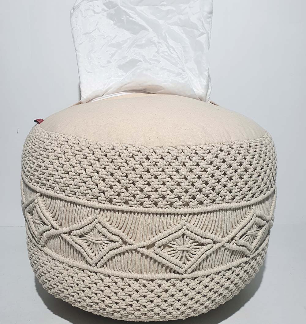 The RAMSHA HOME Round Cotton Pouf PF-072 features a beige textured, woven cotton design with diamond patterns and cozy seating, shown with a white plastic bag on top against a plain white background—ideal for stylish home décor.
