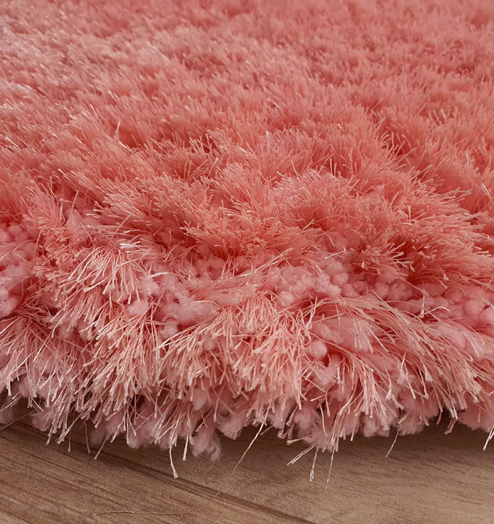 Close-up of the RAMSHA HOME Round Shaped Pink Shaggy Rug - SG 01, featuring a soft plush pile with long fibers, displayed on a wooden floor.