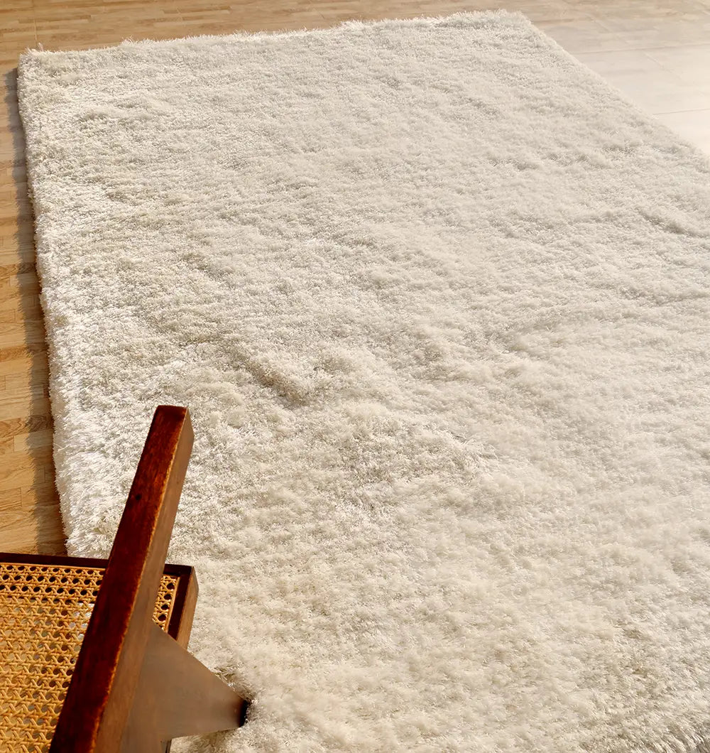 The RAMSHA HOME Plush White Shaggy Rug (SG-011) adds a cozy touch to the light wood floor, while a wooden chair with a woven cane seat peeks in from the lower left.