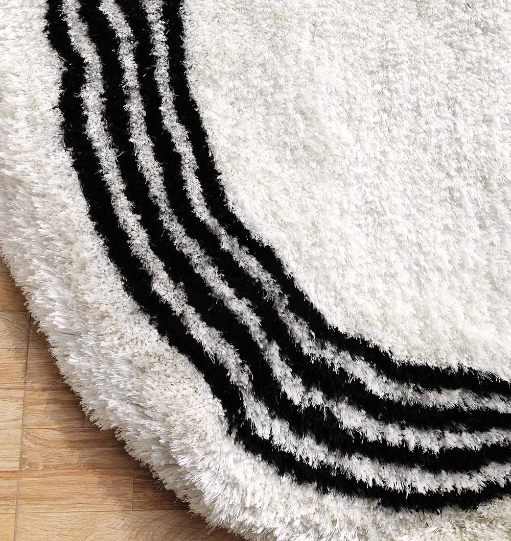 A close-up of the RAMSHA HOME White & Black Shaggy Rug (SG-013), showcasing its modern ivory design with three curved black stripes, elegantly placed on a wooden floor.