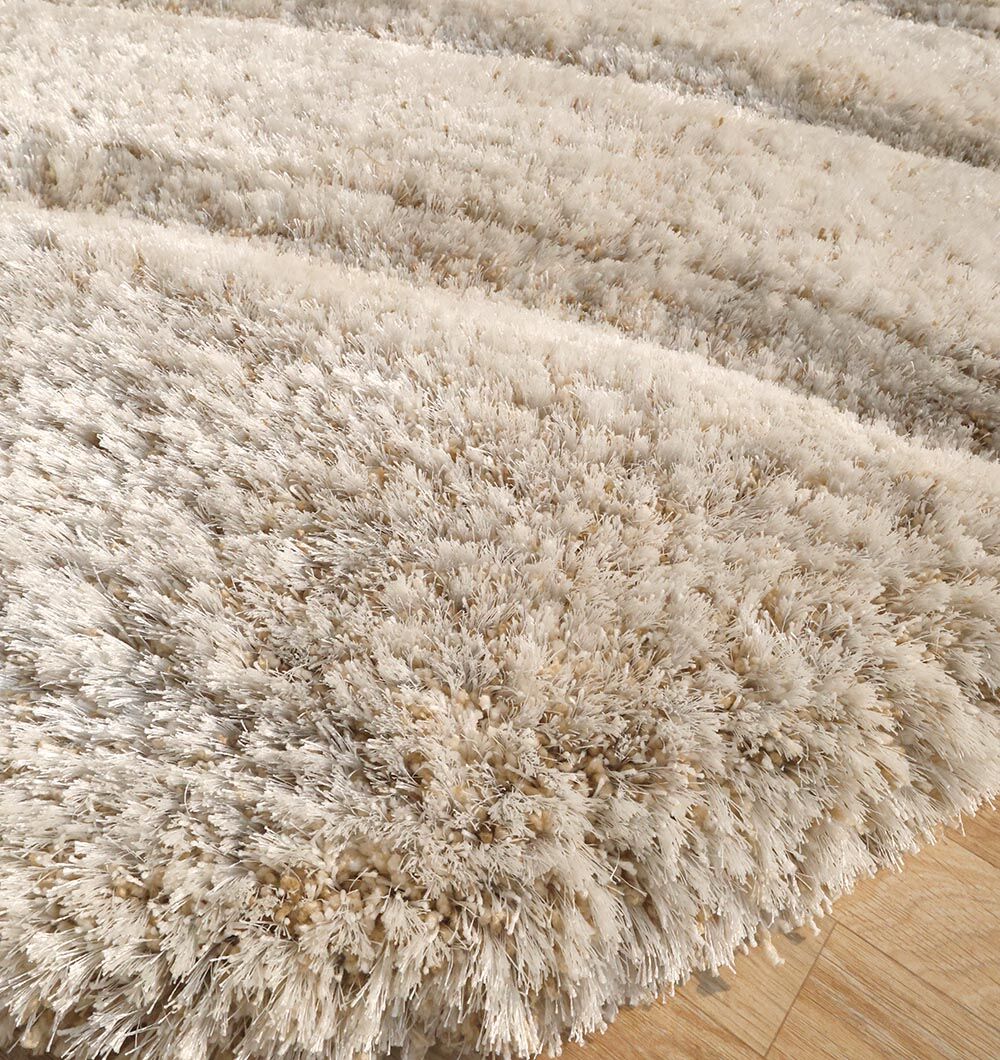 A close-up of the RAMSHA HOME Shaggy Shape Rug for Living Room - SG 017 (200x300 cm), featuring beige wavy patterns and a thick, plush pile on a wooden floor. The soft texture adds an inviting touch to any space.