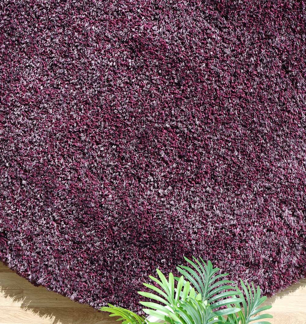 The RAMSHA HOME Shaggy Rug for Living Room - SG 019 features a plush purple and white pile, creating a cozy accent on the wooden floor, with green fern leaves framing the scene in the lower right corner.