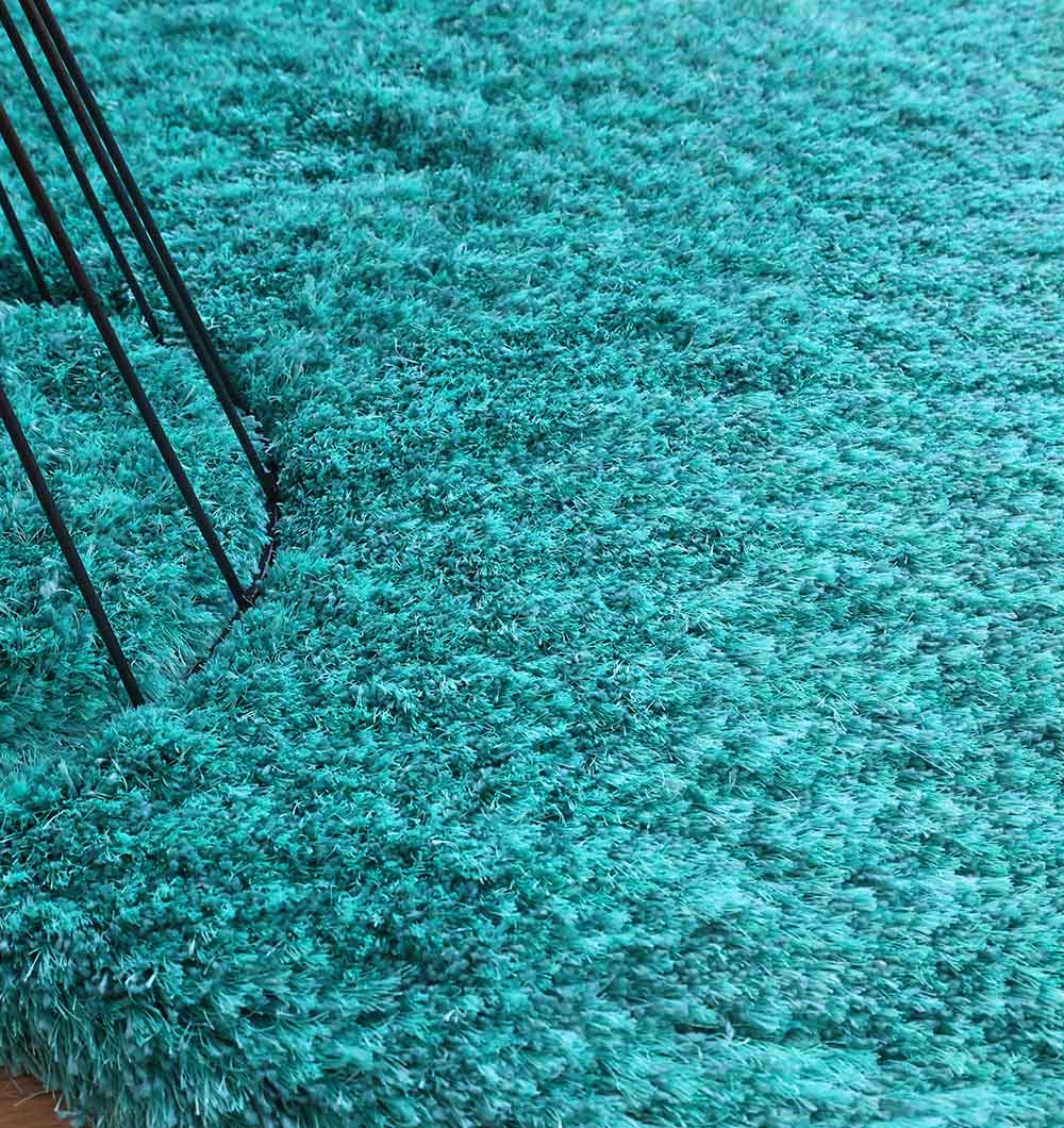 Close-up of the RAMSHA HOME Turquoise Fluffy Shaggy Round Shape Area Rug SG 021, showcasing its soft, thick fibers. Thin black metal furniture legs are partly visible on the left side.