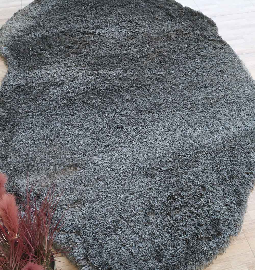 The RAMSHA HOME Shaggy Shape Rug for Living Room - SG 022 (200x300 cm) in plush gray rests on a light wooden floor, with pink dried flowers arranged in the lower left corner.