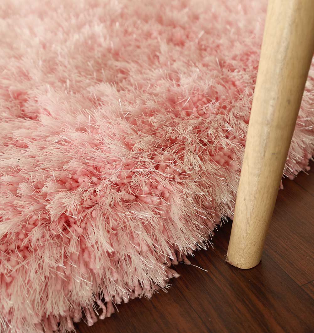 Close-up of the Light Pink Color Home Decor Round Shaggy Rug - SG 02 on a wooden floor, with a light-colored wooden chair leg visible on the right side.