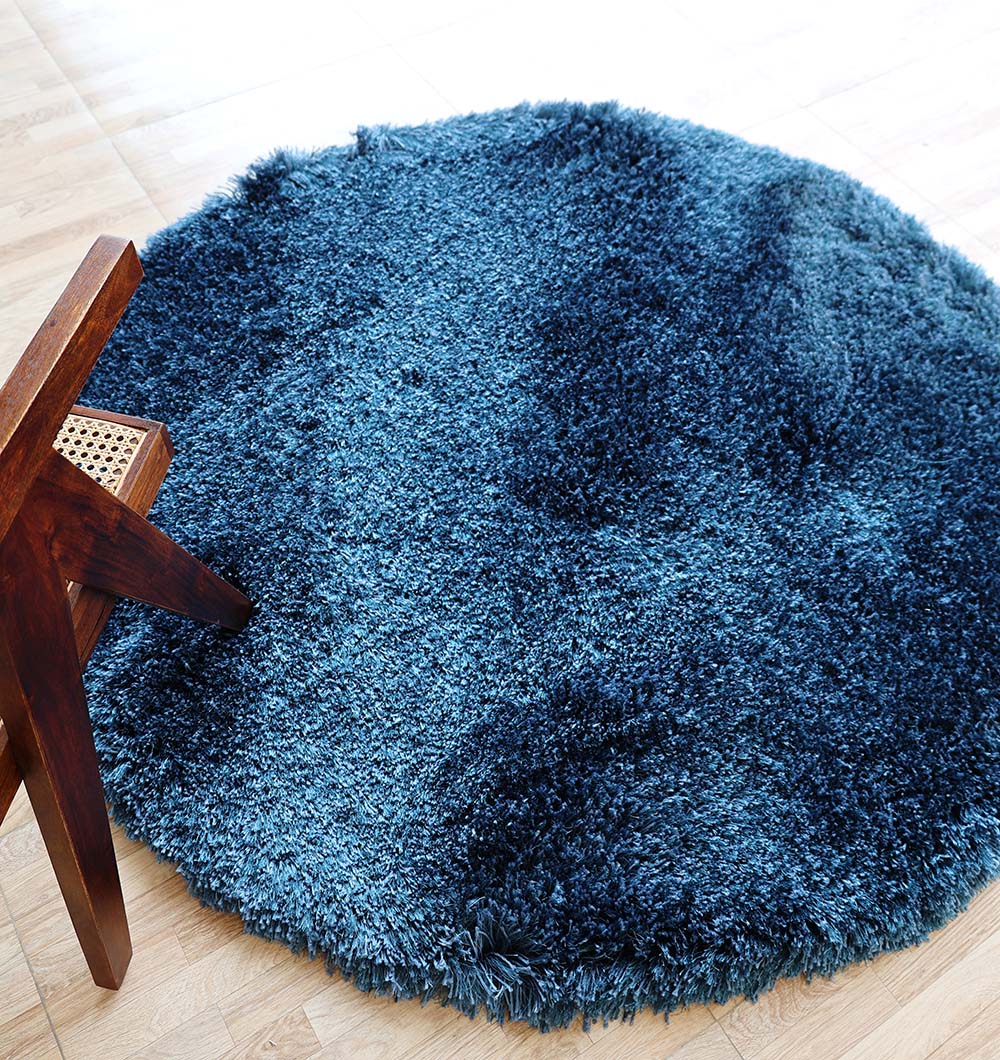 The RAMSHA HOME Blue Color Home Decor Shaggy Rug - SG 024 is laid on a light wooden floor beside a wooden chair with a woven seat.
