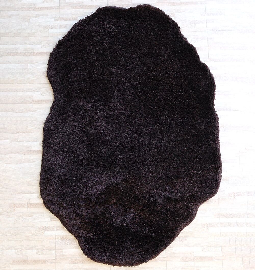 The RAMSHA HOME Dark Brown High-Density Shaggy Rug - SG 028 adds warmth and texture to the room, its irregular shape standing out against the light wooden floor.