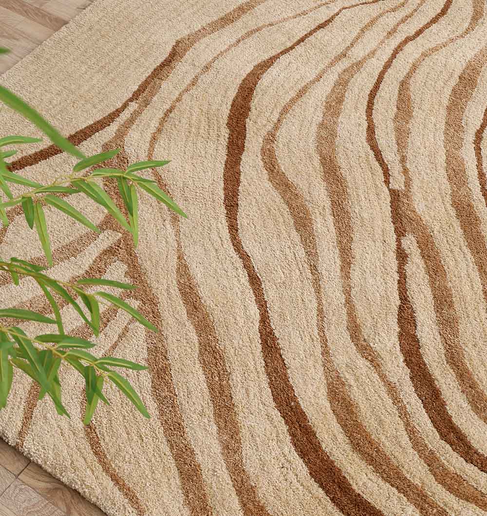 The RAMSHA HOME Rectangle Multi Color Shaggy Rug (SG 031, 200x300 cm) features wavy brown stripes on soft beige, shown here on a light wood floor with a green leafy plant partially visible in the lower left corner.