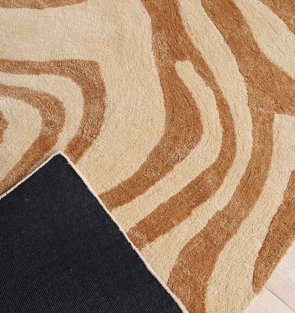 A close-up of the RAMSHA HOME Rectangle Beige & Brown Color Shaggy Rug for Living Room (SG 032, 200x300 cm) shows its wavy zebra-like pattern, plush texture, and a flipped corner revealing the black non-slip backing on a light floor.