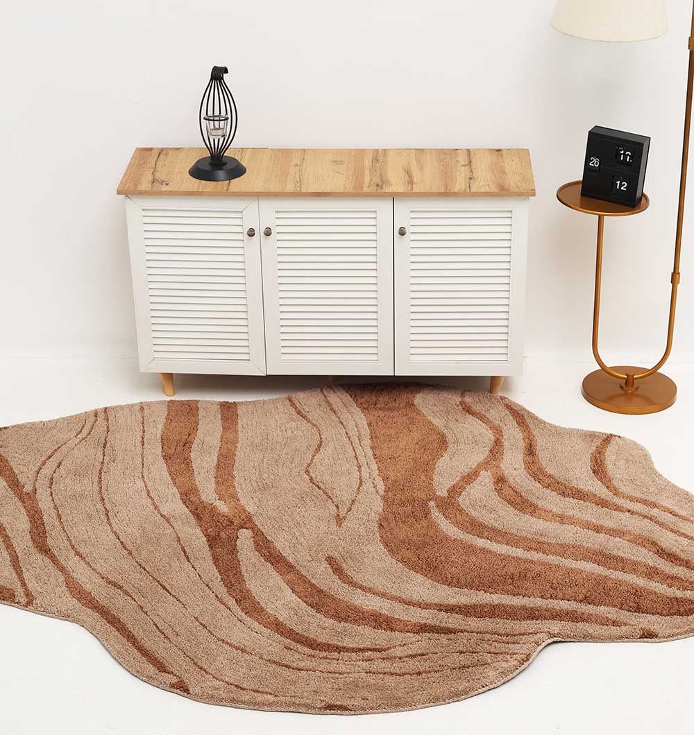 The RAMSHA HOME Shaped Rug Beige & Brown Color Shaggy Rug for Living Room - SG 033 (160x230 cm) adds cozy comfort in front of a white cabinet, complemented by a black lamp, calendar block, and floor lamp on a round gold side table.