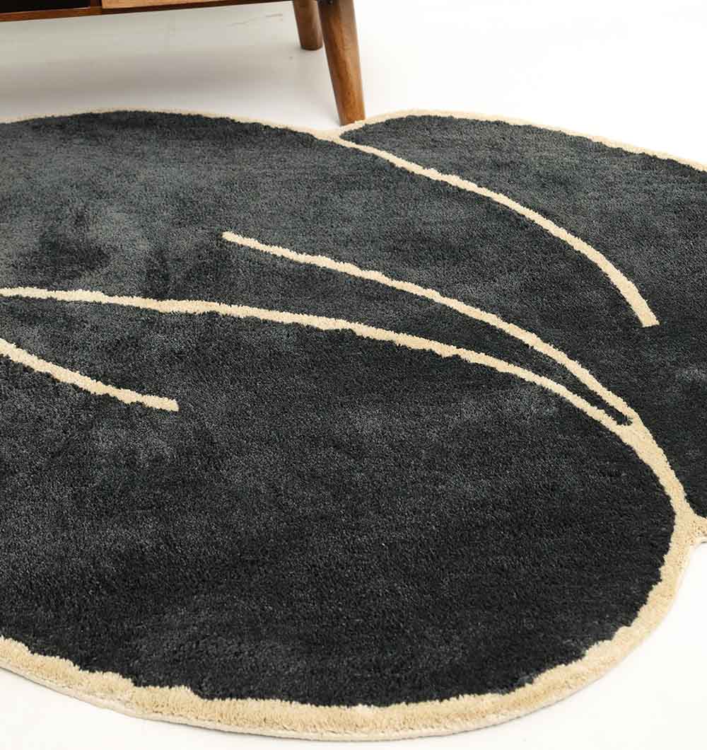 The RAMSHA HOME Black & Gold Color Shaped Shaggy Rug (SG 034, 160x230 cm) adds a modern touch to a white floor near wooden furniture.