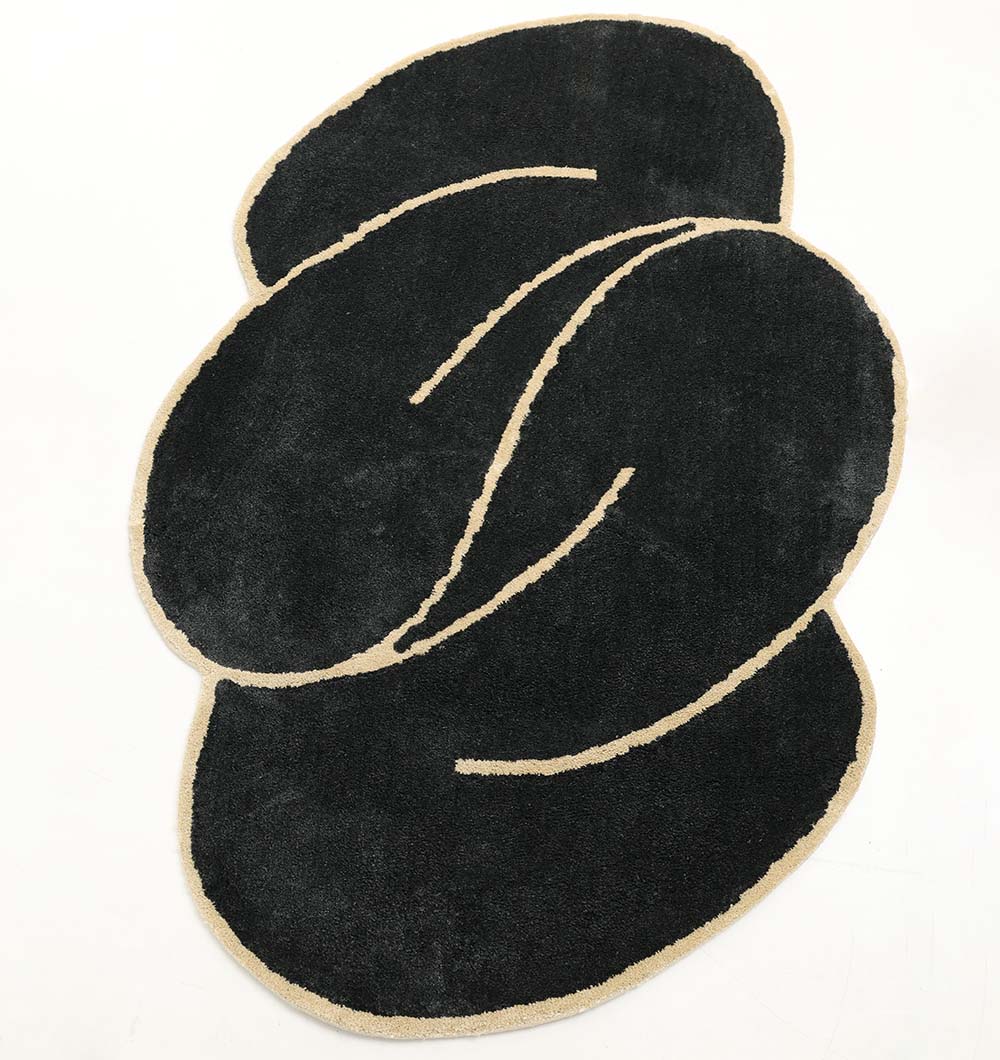 The RAMSHA HOME Black & Gold Color Shaped Shaggy Rug for Living Room - SG 034 (160x230 cm) features irregular, overlapping shapes and curved lines in black, gold, and beige tones against a white background.