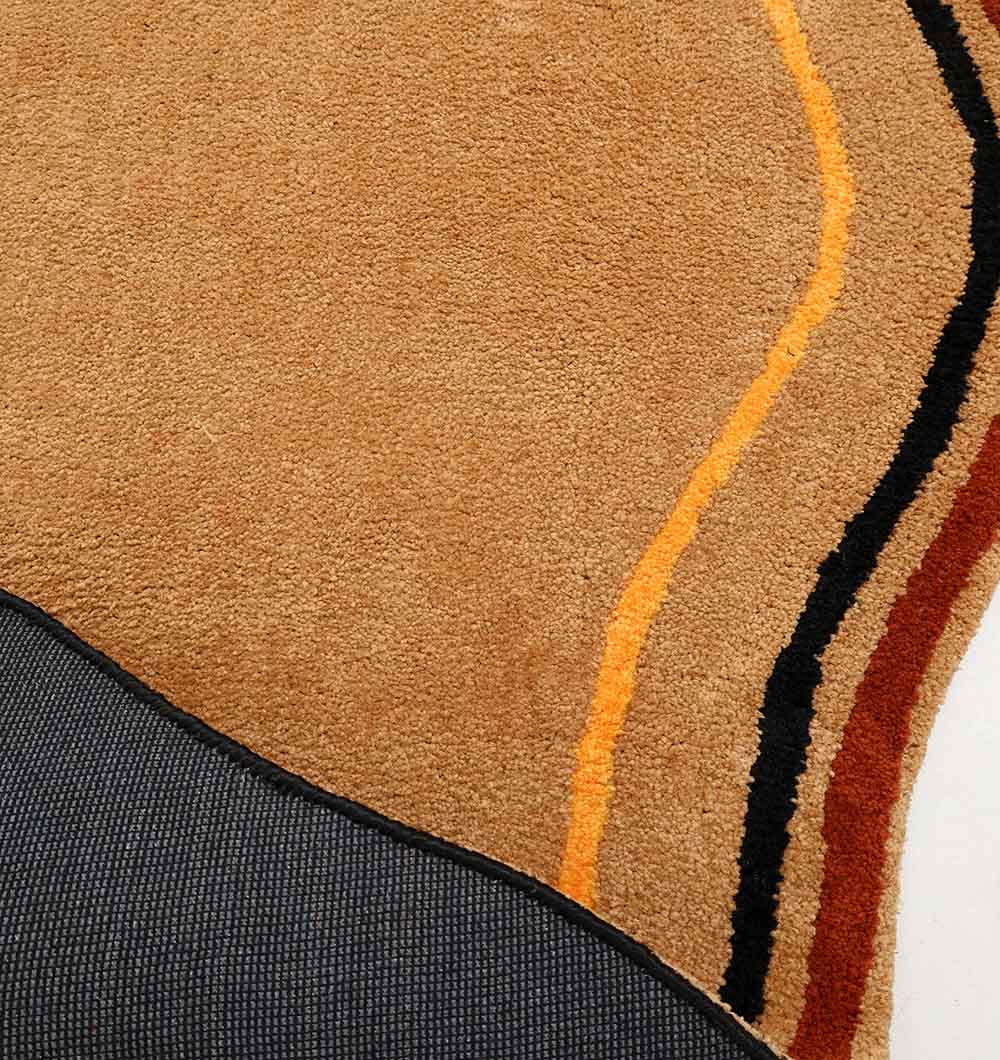 A close-up of the RAMSHA HOME Shaped Rug Multi Color Shaggy Rug for Living Room (160x230 cm), featuring abstract curved lines in brown, tan, and orange shades, with a glimpse of its textured dark backing in one corner.