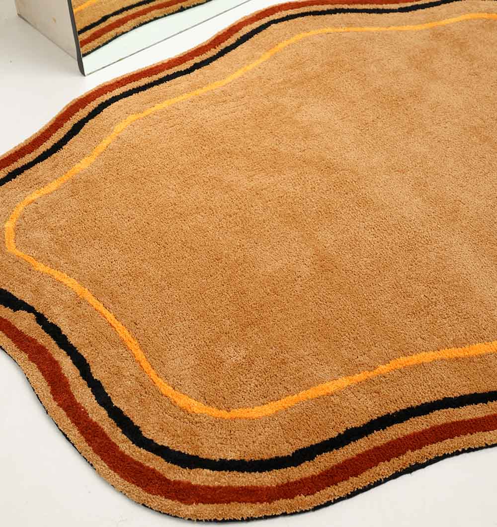 The RAMSHA HOME Shaped Rug Multi Color Shaggy Rug for Living Room (SG 035, 160x230 cm) features wavy edges and curved orange, black, and brown stripes along the border, shown on a white floor next to a mirror.