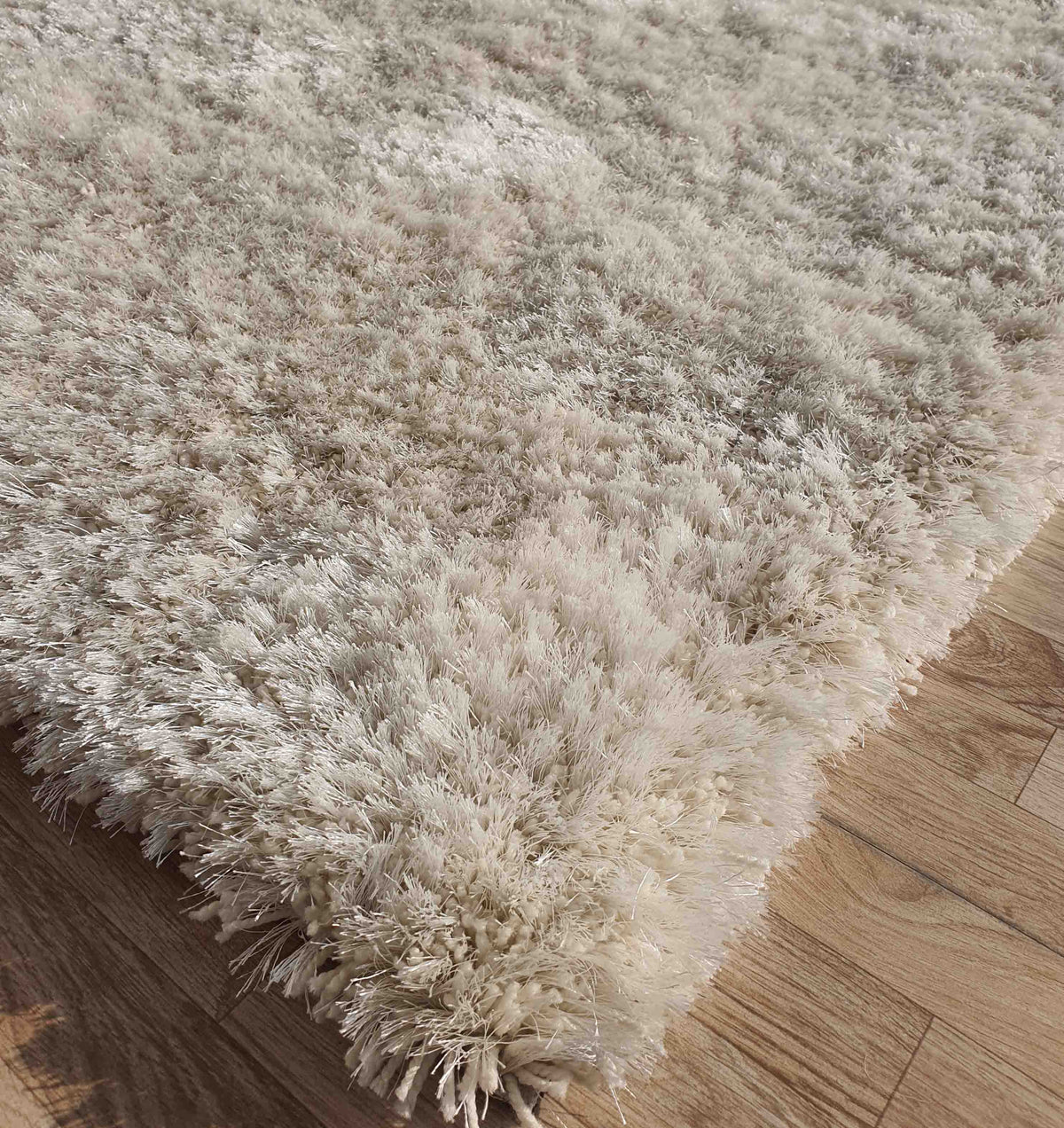 A close-up of the RAMSHA HOME Gold Color Shaggy Area Rug for Large Living Room - SG 03 B on a wooden floor, highlighting its thick, soft, and fluffy texture with plush fibers that enhance a cozy atmosphere.