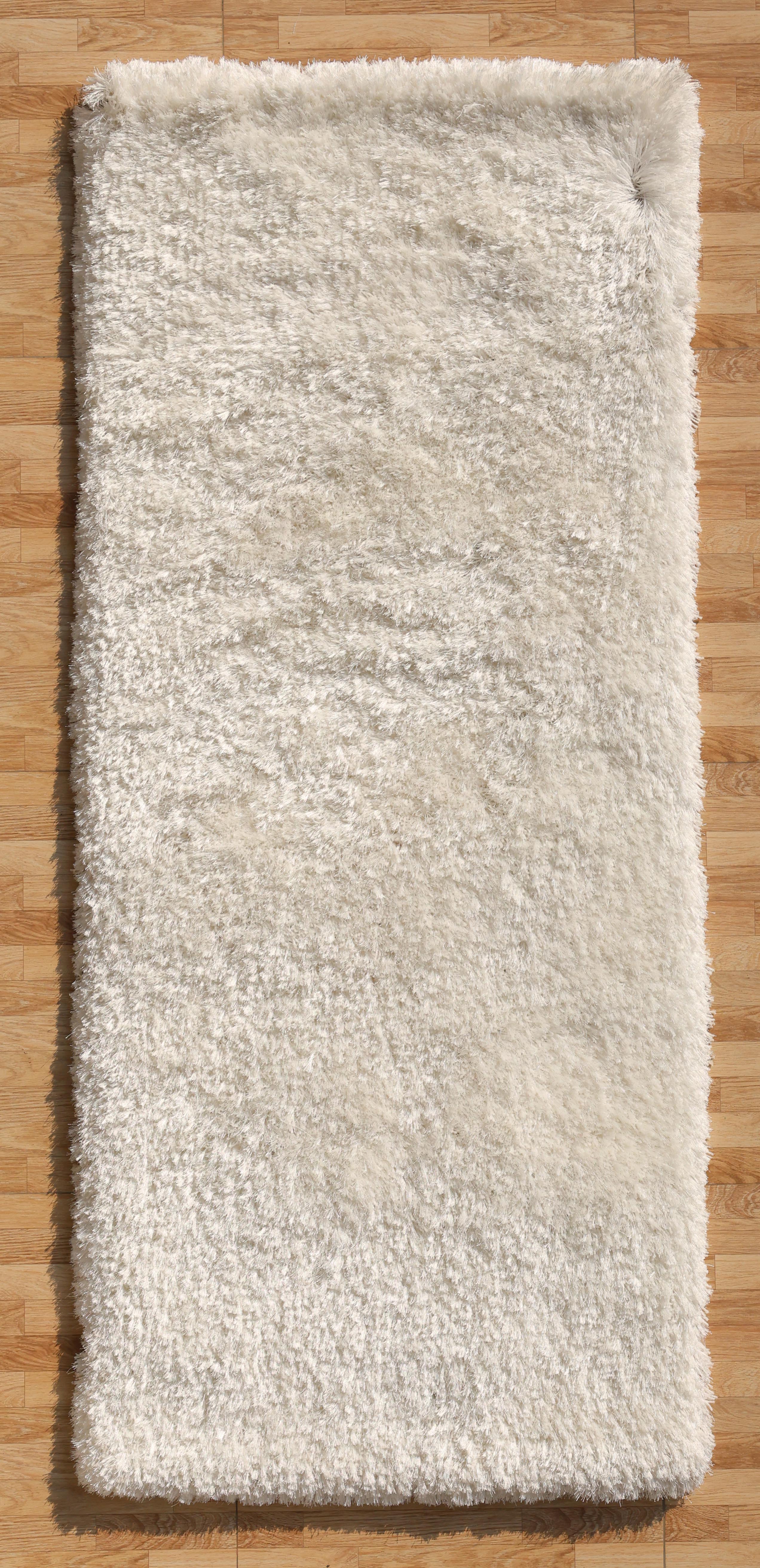 The RAMSHA HOME White Color Plush Shaggy Area Rug - SG 040, with its soft texture and plush fibers, is shown from above on a light brown wooden floor, creating a cozy atmosphere.