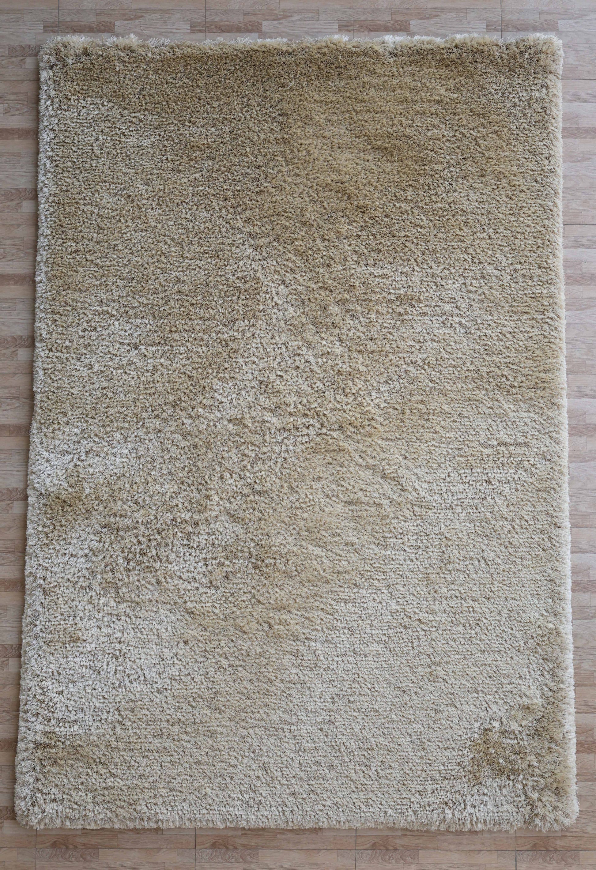The Modern Ultra Soft Shaggy Carpet for Bedroom - SG 041 by RAMSHA HOME is a large, rectangular beige rug with a fluffy texture and subtle color variations, perfect for modern interiors on light wood floors.