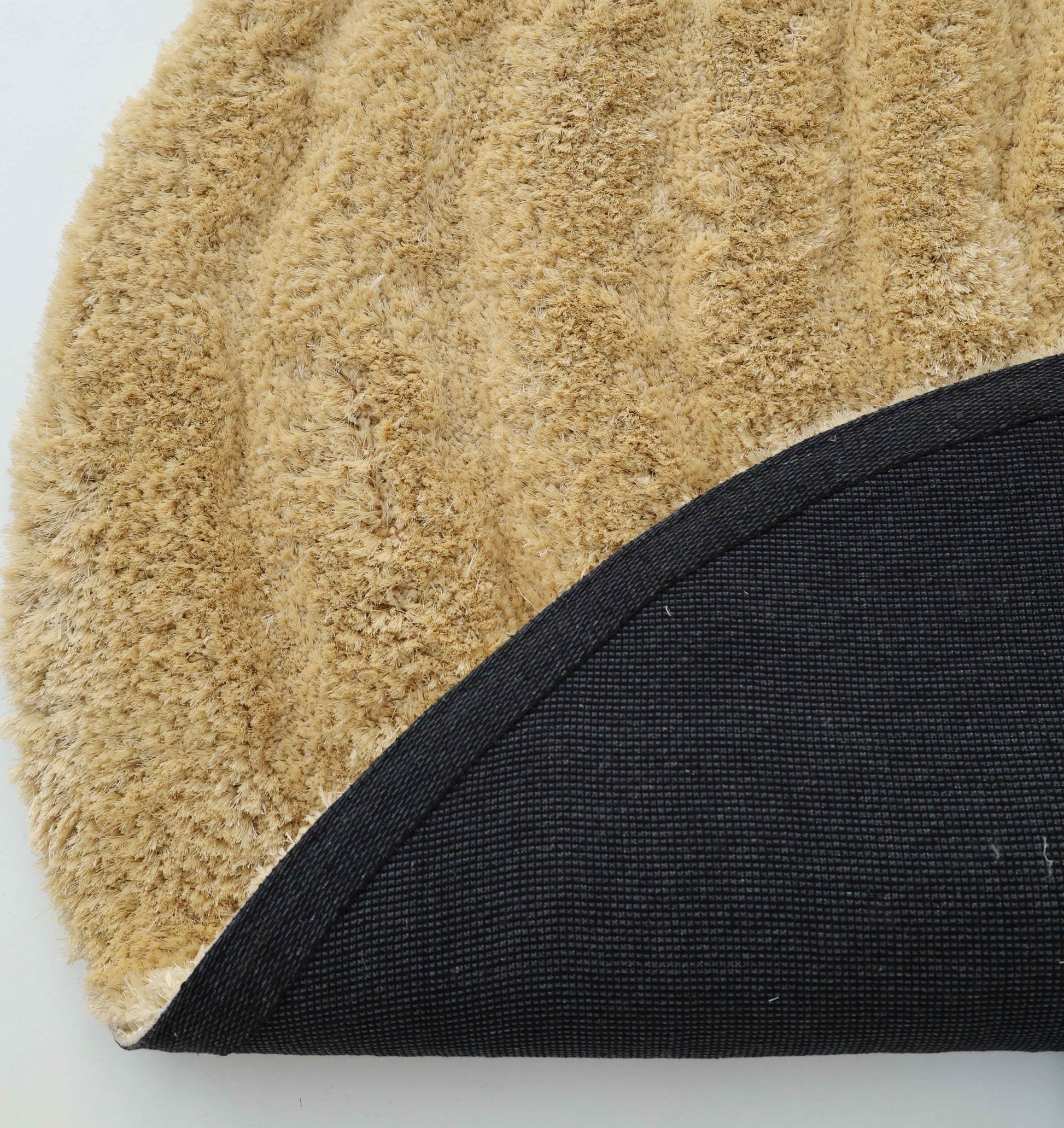 Close-up of the Gold Irregular Shaped Home Decor Shaggy Rug - SG 041 3D by RAMSHA HOME, with tan textured surface and curved black non-slip backing—ideal for adding unique shape and 3D shag texture to your space.