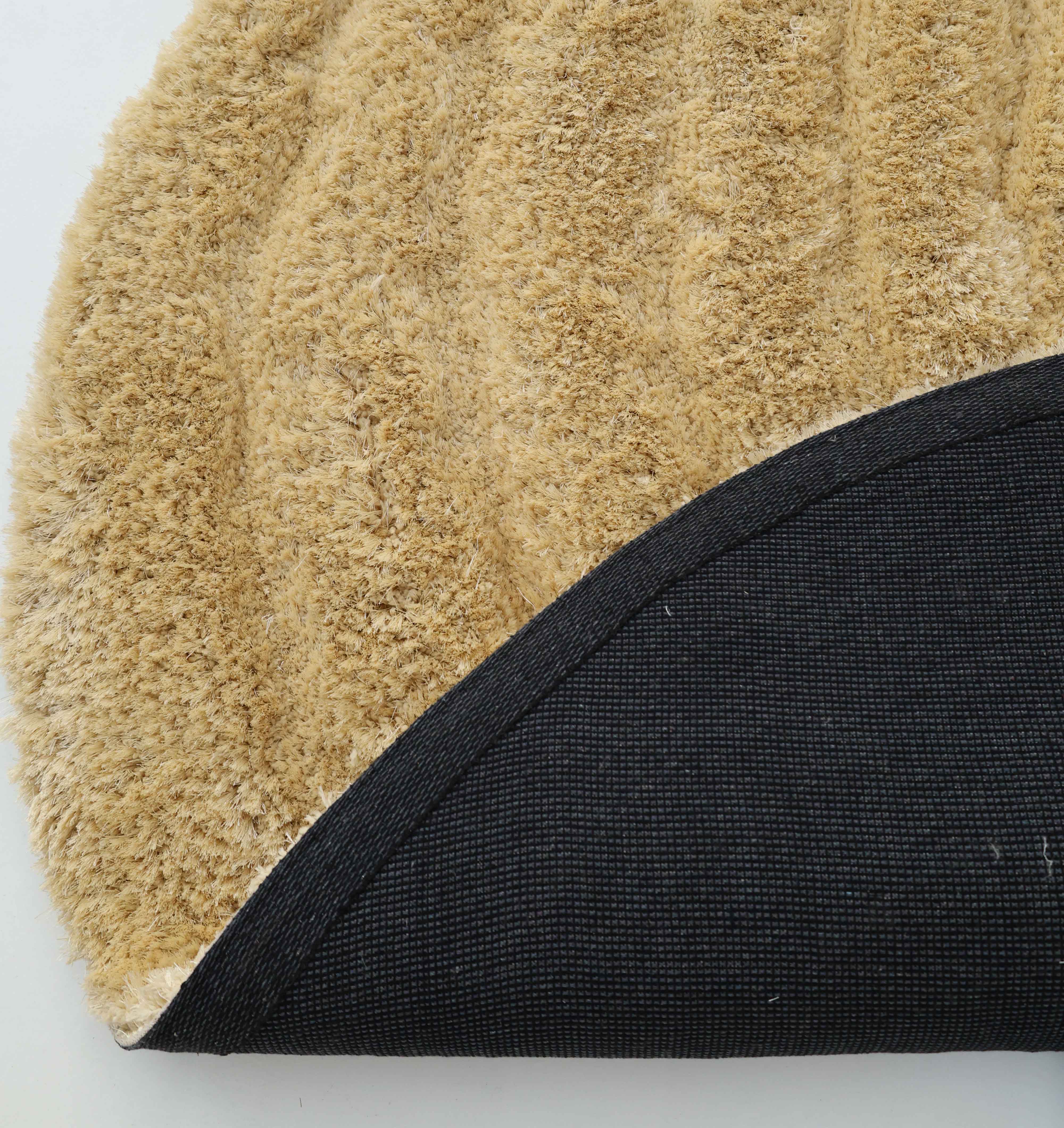 Close-up of the Gold Irregular Shaped Home Decor Shaggy Rug - SG 041 3D by RAMSHA HOME, with tan textured surface and curved black non-slip backing—ideal for adding unique shape and 3D shag texture to your space.