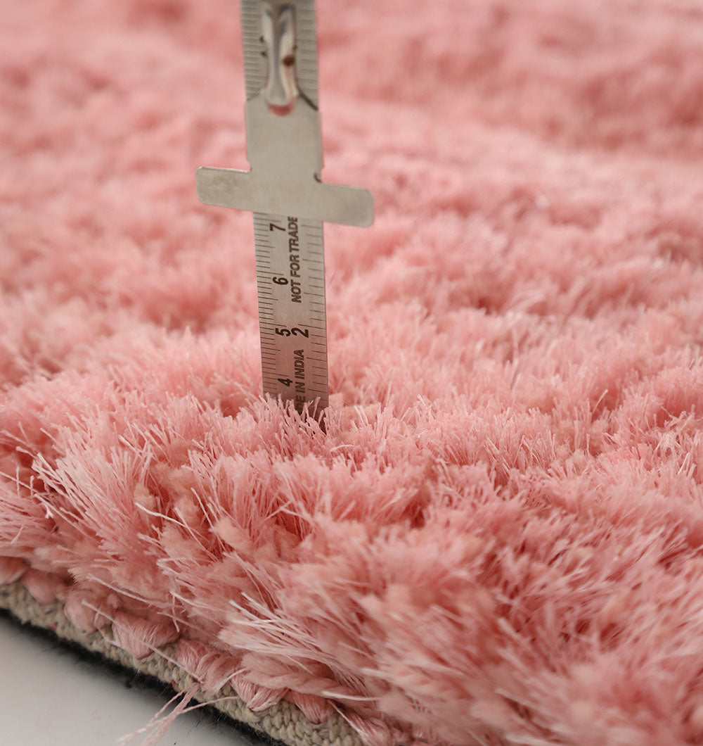 A close-up of a metal ruler measuring the height of the fluffy fibers on the RAMSHA HOME Gold Irregular Shaped Home Decor Shaggy Rug - SG 042 3D, highlighting its thick, soft pink texture.