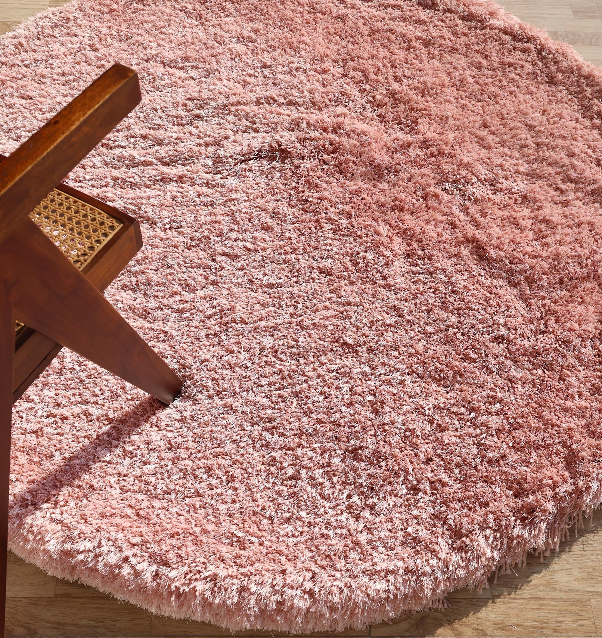 The RAMSHA HOME Modern Ultra Soft Pink Shaggy Carpet (SG 042) is shown on a light wood floor, with part of a wooden chair featuring a woven cane seat visible on the left.