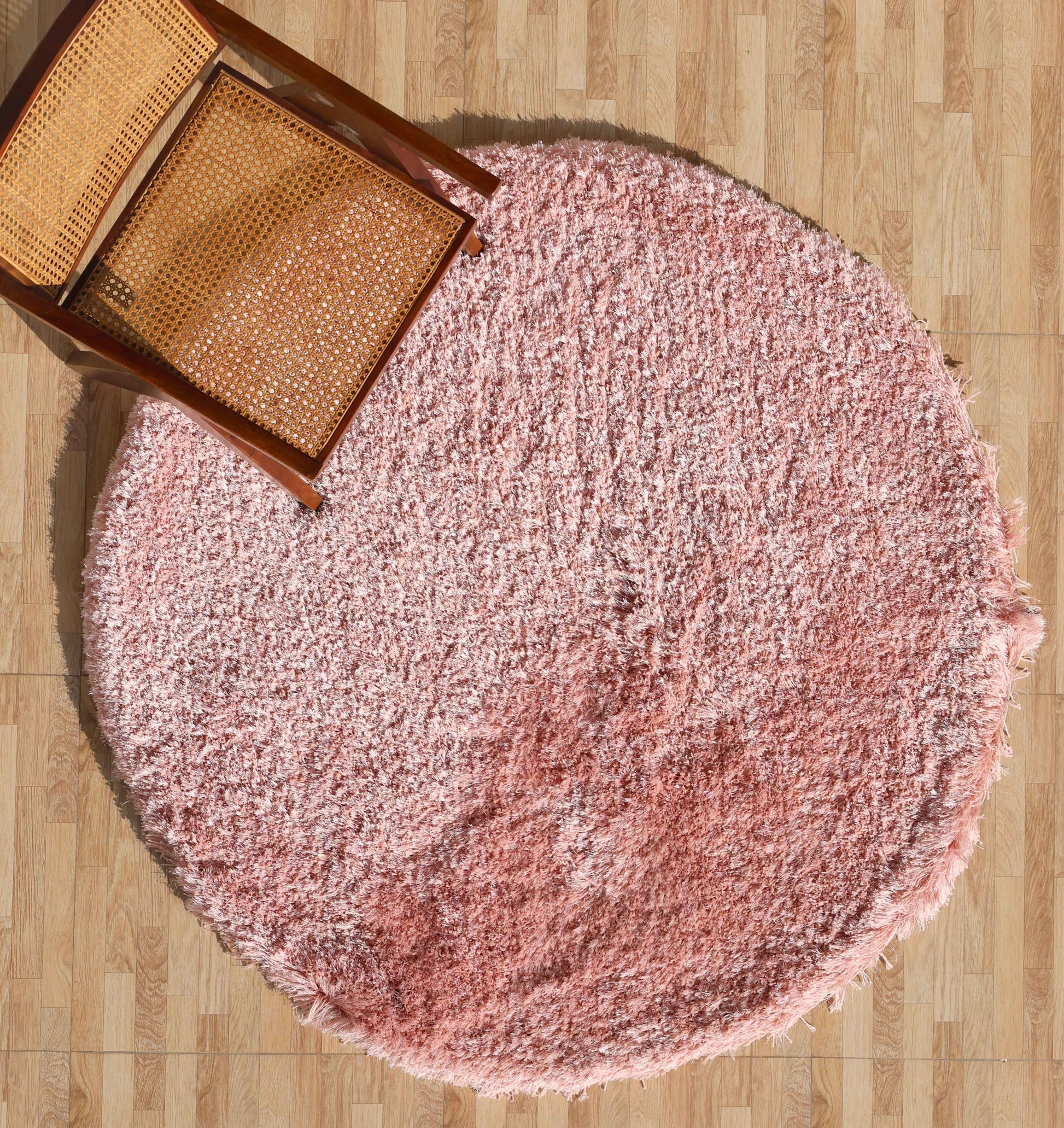 The RAMSHA HOME Modern Ultra Soft Pink Color Shaggy Carpet for Bedroom - SG 042 is placed on a wood-patterned floor with a wooden chair featuring a woven seat partially positioned on the rug in the top left corner.