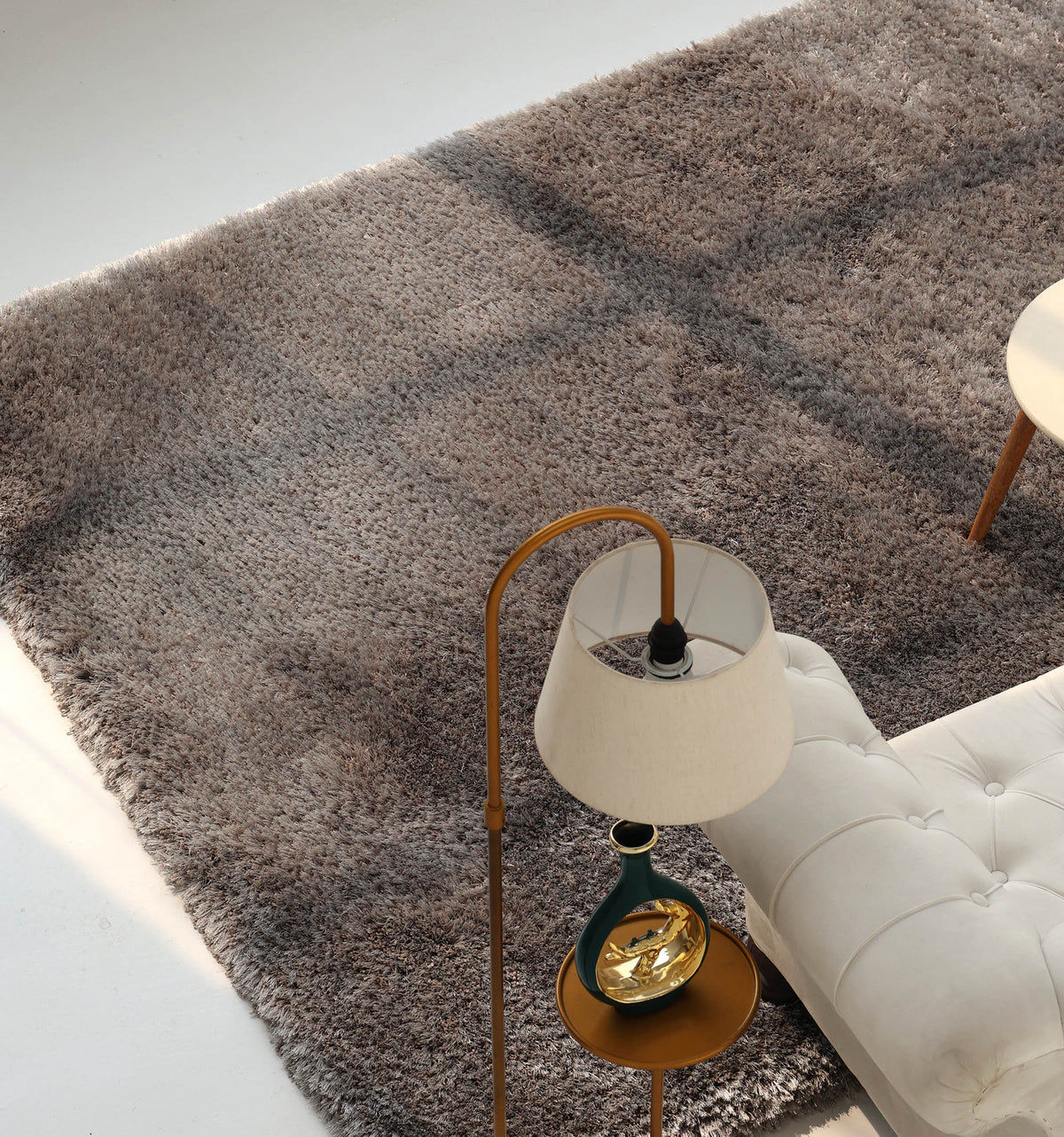 A beige tufted sofa, a modern floor lamp with a round table, and the RAMSHA HOME Soft Plush Grey Shaggy Rug for Living Room - SG 044 in textured gray on a light floor, viewed from above.