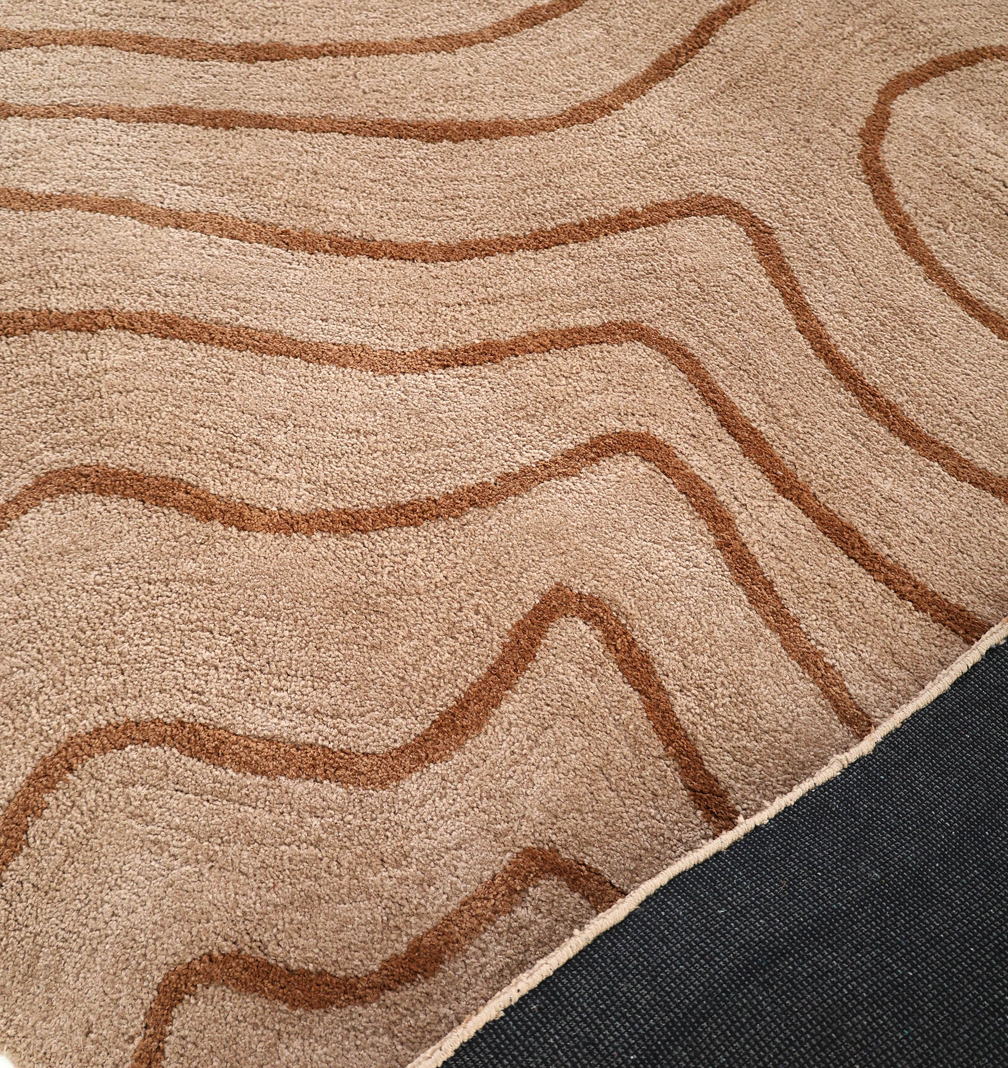 The RAMSHA HOME Designer Contour Line Plush Area Rug - SG 051 features a modern beige brown design with wavy lines and a black non-slip backing, adding contemporary style and comfort to any room.