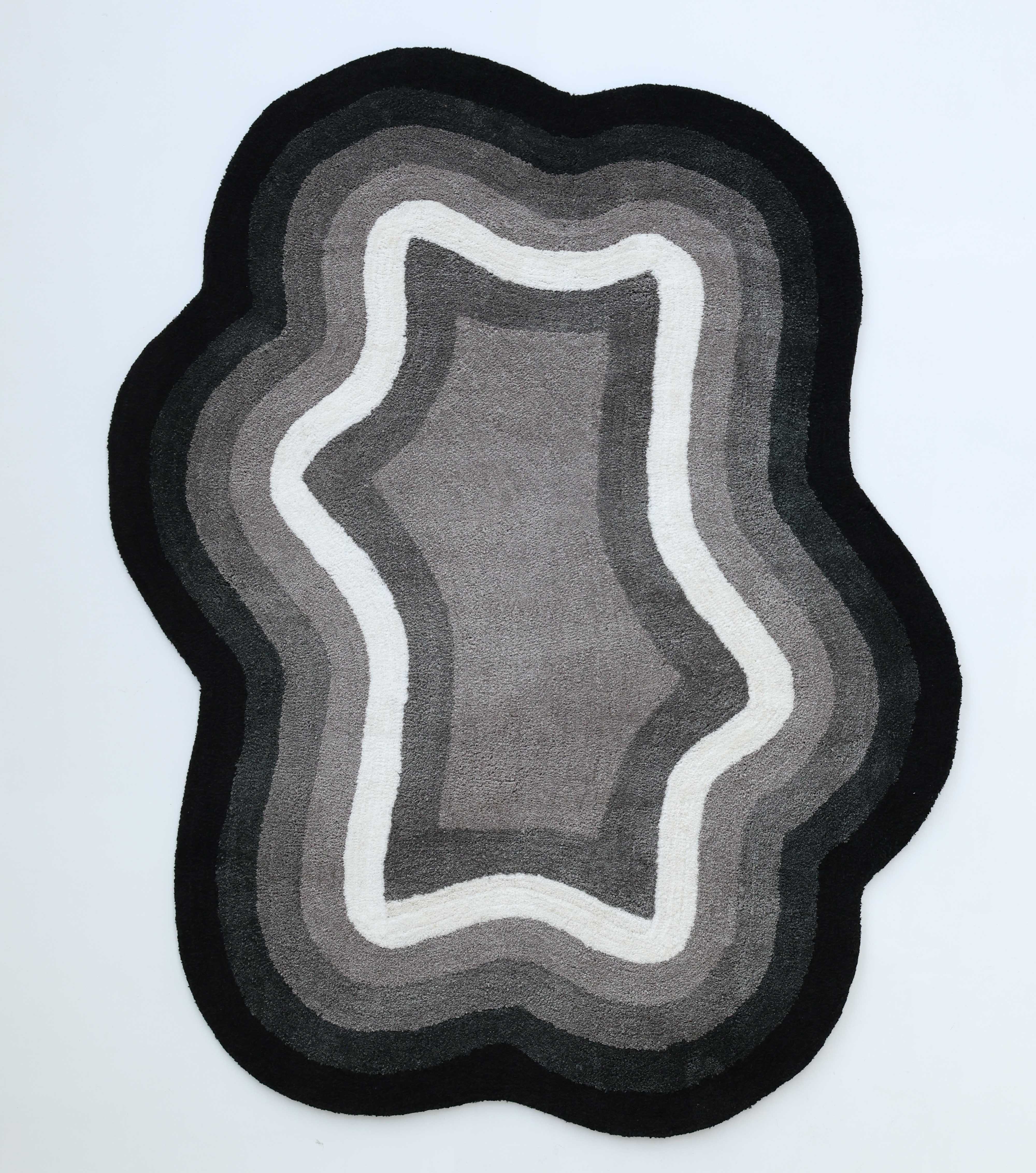 The RAMSHA HOME Modern Border Layered Irregular Soft Shaggy Carpet - SG 054 features abstract, wavy concentric layers in black, gray, and white on a light background, resembling topographic lines for a stylish modern look.